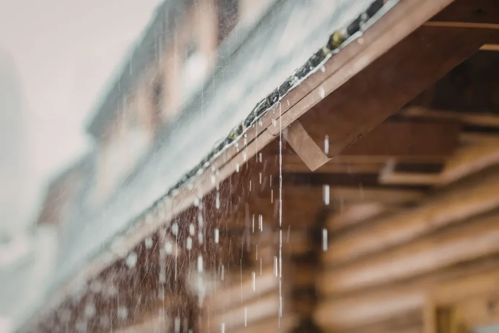 Eau de pluie ruisselle d’un toit en bois