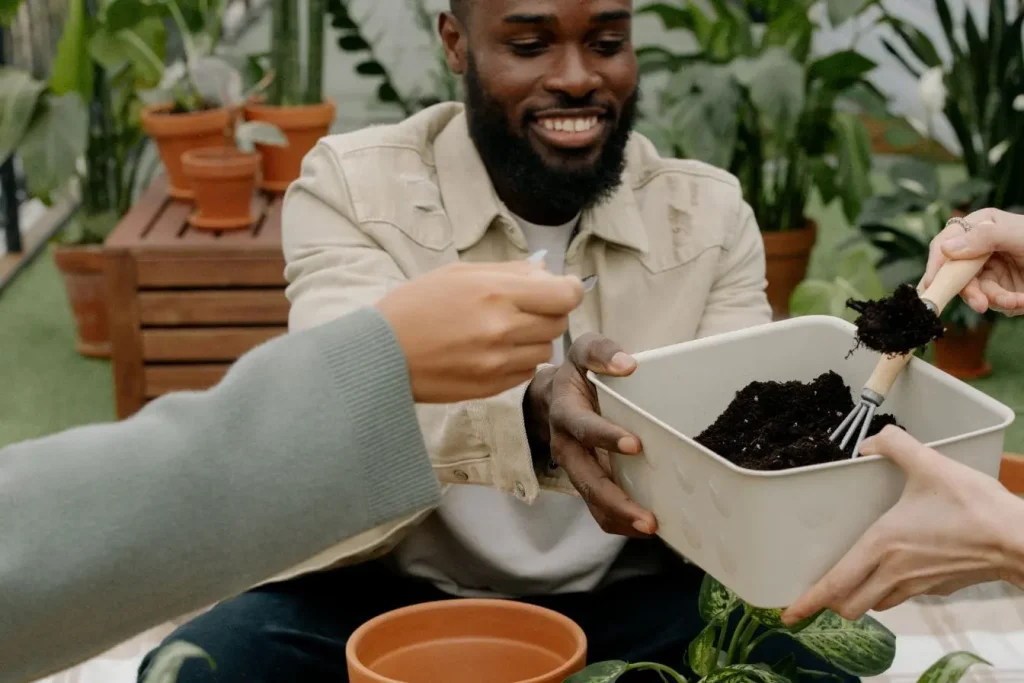 Gros plan sur mains tenant outil de jardinage, symbole de la création d’un lombricomposteur et du soin apporté au compost maison.