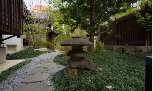 Jardin verdoyant avec lanternes et pierres plates, image qui illustre la création d’un chemin en pas japonais pour structurer l’espace.