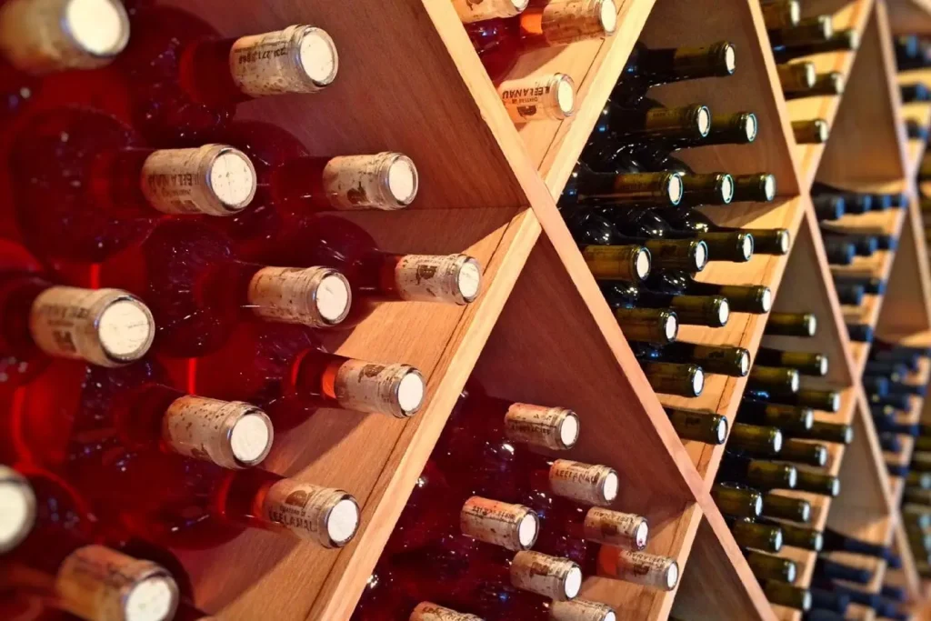 Casier en bois avec compartiments diagonaux remplis de bouteilles, image qui illustre l’organisation idéale pour aménager un cellier en cave.