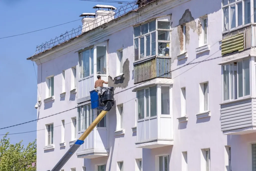 Ouvrier appliquant enduit sur façade, image représentative d’une remise en état avec peinture.