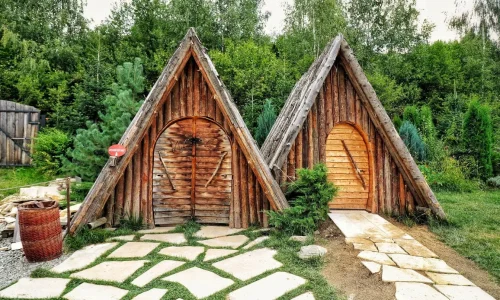 Deux cabanes triangulaires en bois sur allée pavée, reflet d’un espace pratique pour ranger les outils de jardin.