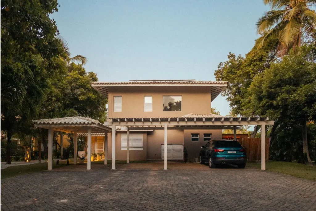 Maison moderne avec carport en bois blanc, image qui illustre la possibilité d’installer soi-même une structure pratique et esthétique pour protéger son véhicule.