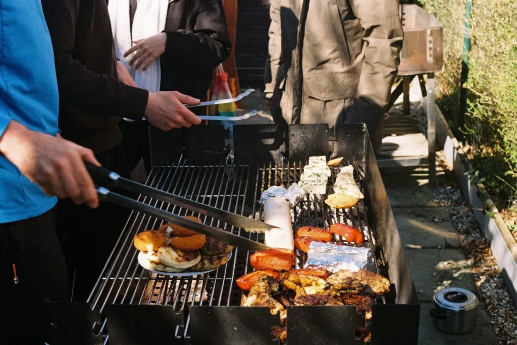 Groupe de personnes réunies autour d’un barbecue dans un jardin, reflet d’un coin barbecue convivial et chaleureux.