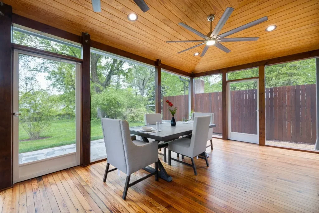 Véranda lumineuse avec grande table dressée et vue sur jardin, image qui illustre un coin repas extérieur convivial et moderne.