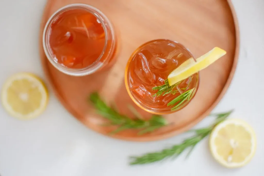 Deux verres remplis de boisson ambrée avec glaçons et rondelles de citron, image qui illustre la fraîcheur d’un kombucha maison.