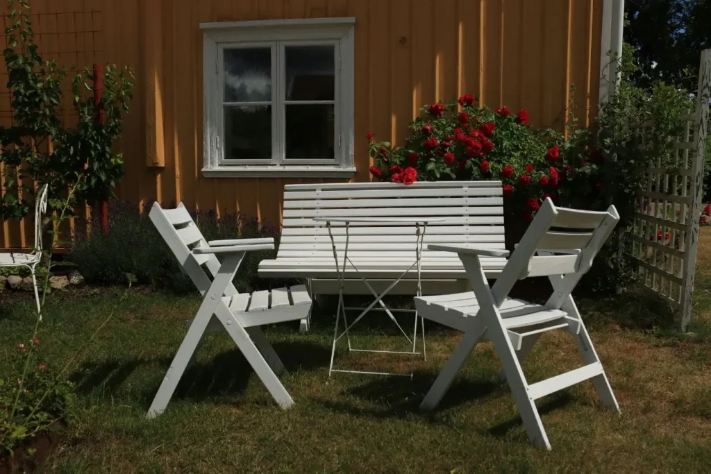 Table métallique entourée de mobilier en bois, image qui traduit l’entretien régulier du teck.