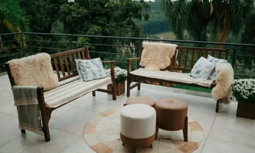 Bancs en bois disposés en L avec coussins décoratifs, reflet du charme d’un salon de jardin en teck bien entretenu.