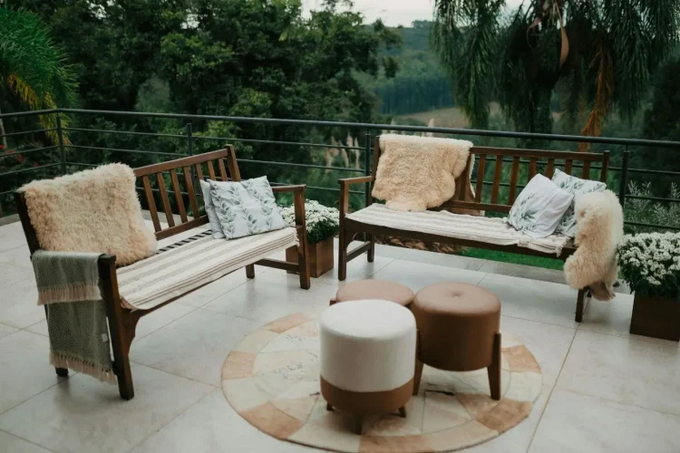 Bancs en bois disposés en L avec coussins décoratifs, reflet du charme d’un salon de jardin en teck bien entretenu.