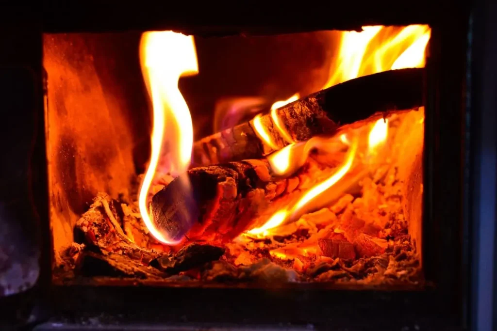 Bois en combustion avec braises incandescentes et cendres, image claire illustrant l’entretien d’un poêle à bois.