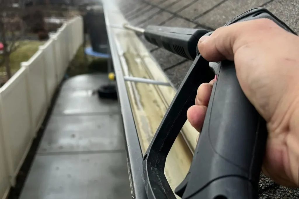 Nettoyage de gouttière avec lance haute pression, image claire d’un entretien régulier.