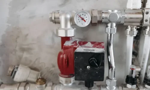 Gros plan sur un circuit de chauffage avec pompe rouge et manomètre, image d’un désembouage pour améliorer la circulation et l’efficacité.