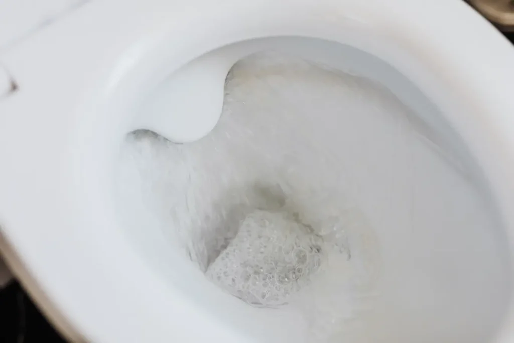 Cuvette blanche avec eau tourbillonnante, symbole des alternatives naturelles pour déboucher des toilettes.