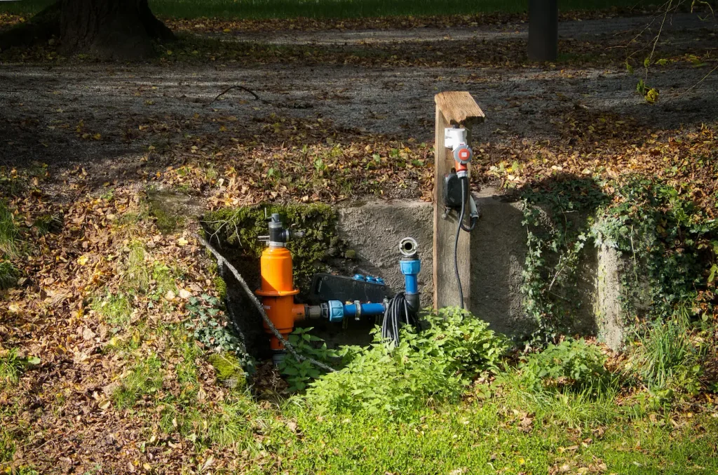 Installation extérieure avec tuyaux orange et bleus reliés à vannes, symbole des étapes pratiques pour installer une pompe de relevage.