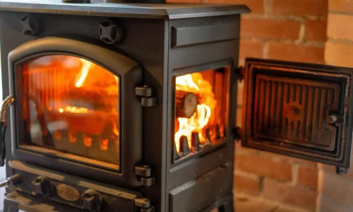 Poêle en fonte noire avec flammes visibles derrière vitre, reflet des gestes essentiels pour l’entretien d’un poêle à bois.