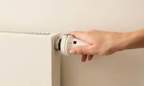 Main ajustant molette numérotée d’un radiateur blanc, reflet des gestes liés à l’entretien et à la purge d’un radiateur de chauffage.
