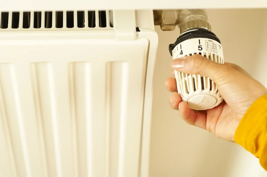 Gros plan sur une main réglant une vanne de radiateur, image d’un désembouage de chauffage central pour améliorer la circulation et la chaleur.