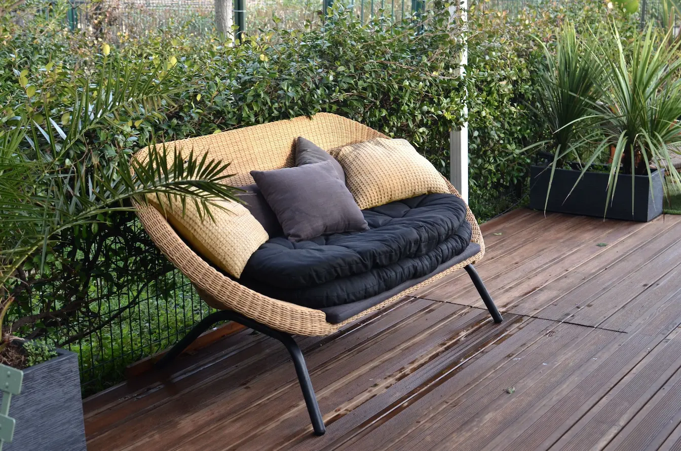 Gros plan sur assise en résine tressée avec coussins épais, image claire illustrant un choix durable pour l’extérieur.