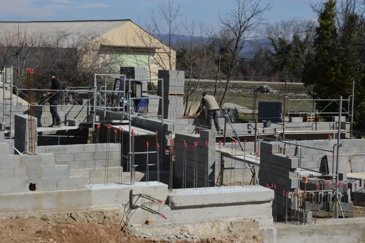 Chantier avec fondations en parpaings et armatures métalliques, symbole des étapes pour construire un mur solide.