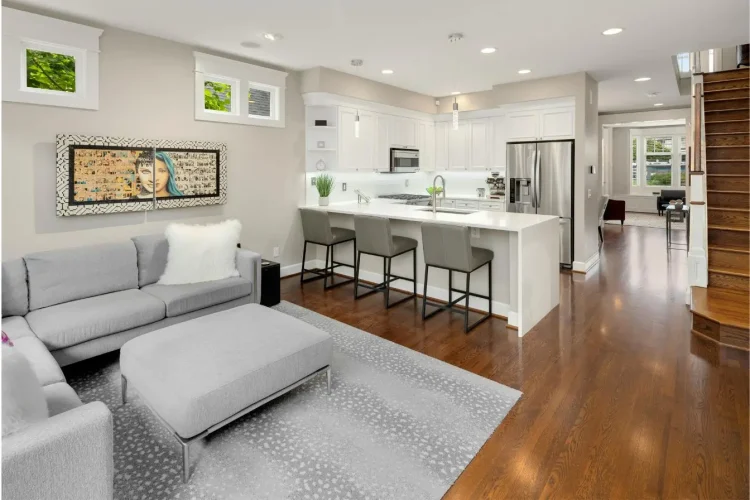 Un grand salon moderne ouvert sur une cuisine équipée avec un îlot central et des tabourets hauts, pour estimer le prix d'une cuisine ouverte sur salon.