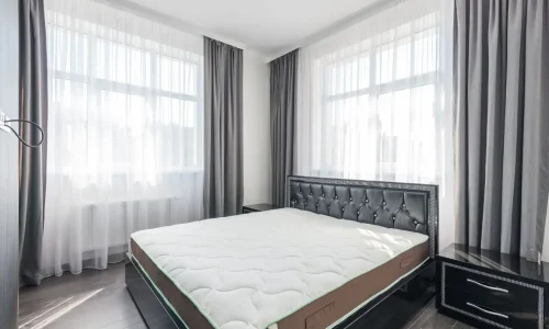 Une chambre lumineuse dotée d'un grand lit à la literie épaisse, idéale pour comparer la différence entre matelas mémoire de forme et ressorts.