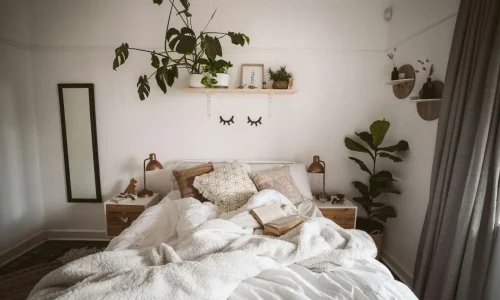 Une chambre cosy avec un lit défait et des plantes vertes, illustrant le manque de confort causé par un symptôme d'une literie trop vieille.