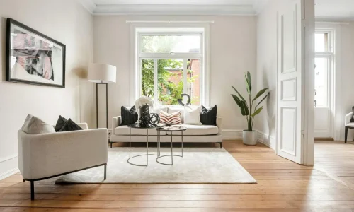 Un grand tapis de salon clair sous le canapé et le fauteuil pour structurer harmonieusement l'espace.